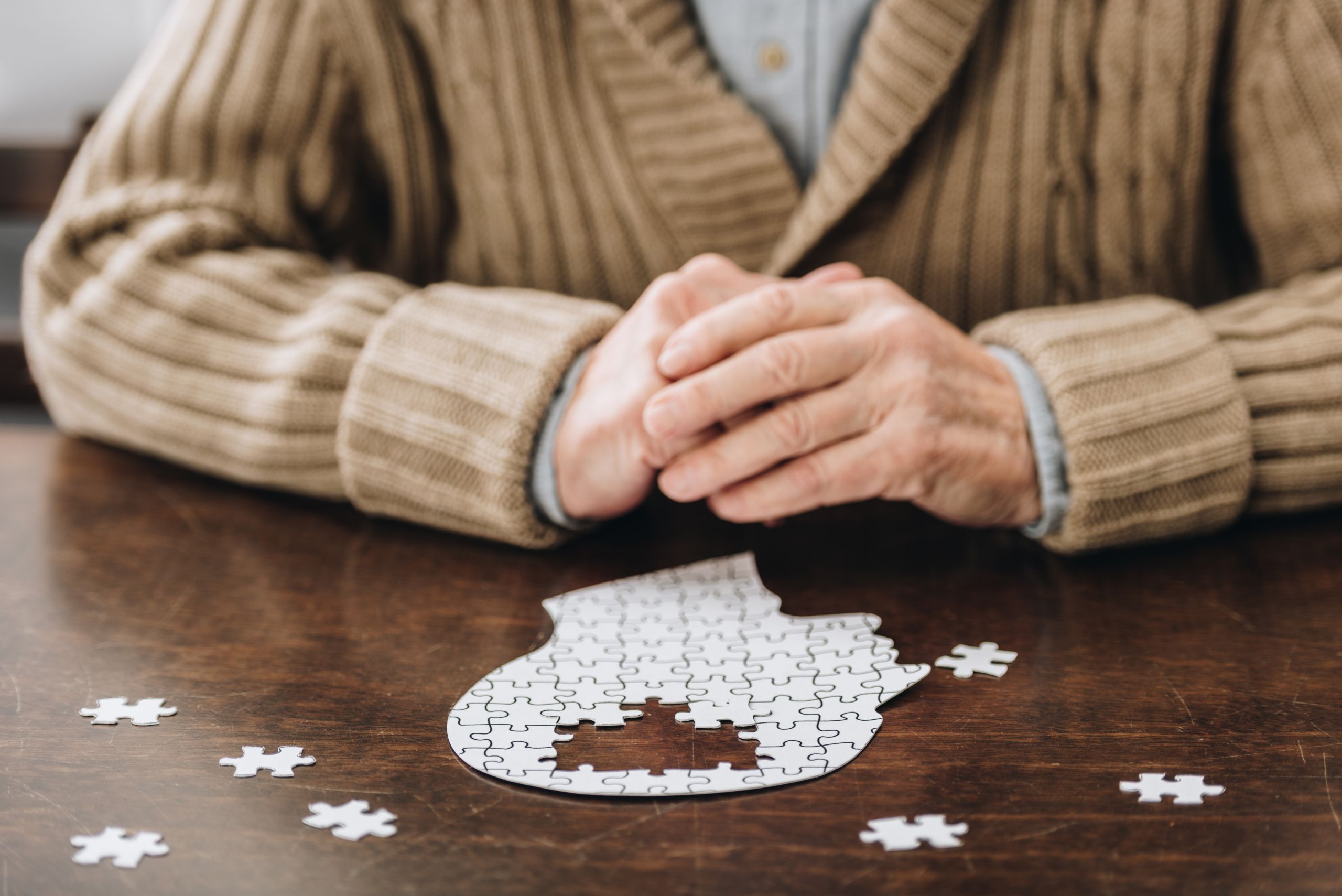 cropped view of senior man playing with puzzles on table